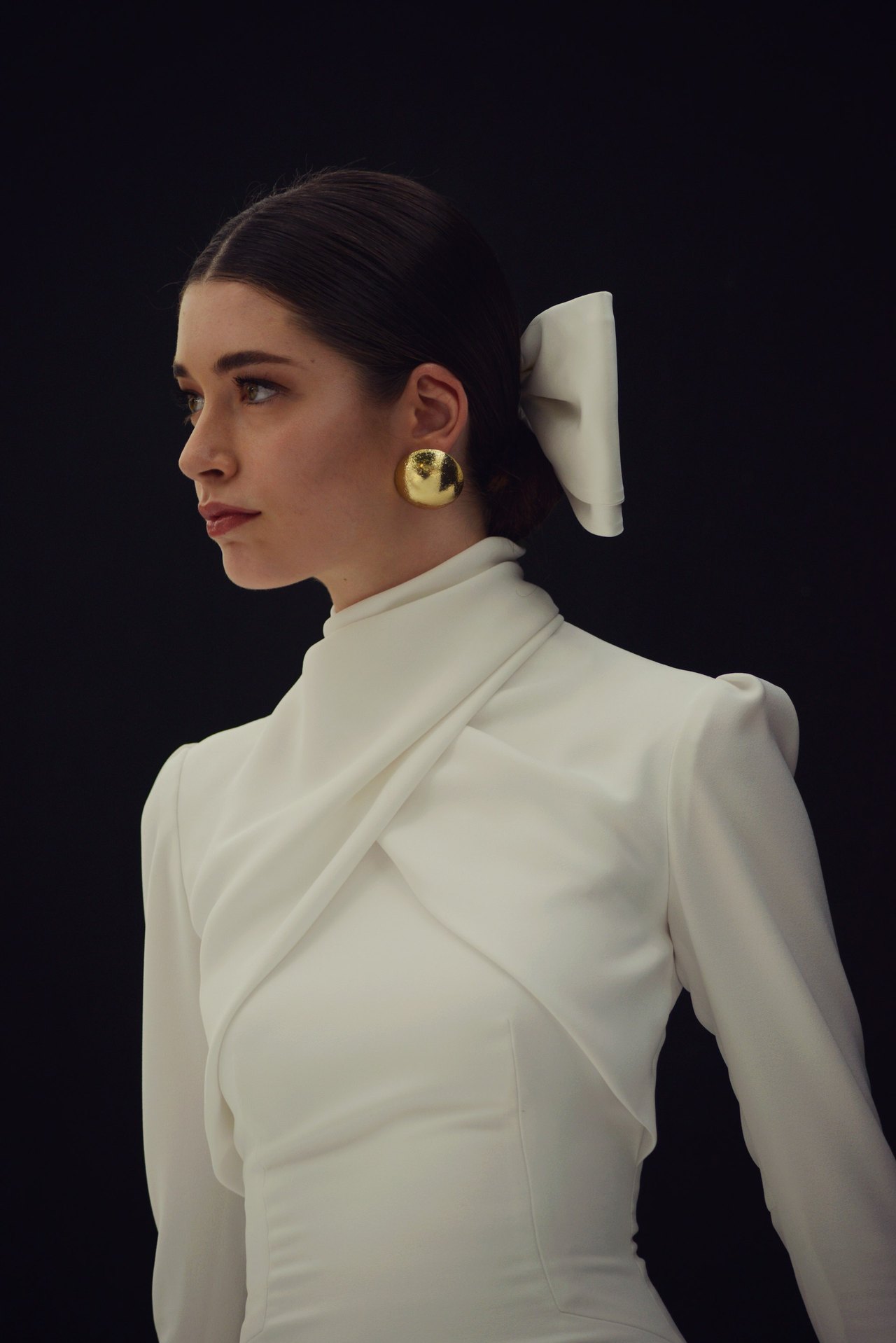 Model im weißen Kleid mit Goldohrringen